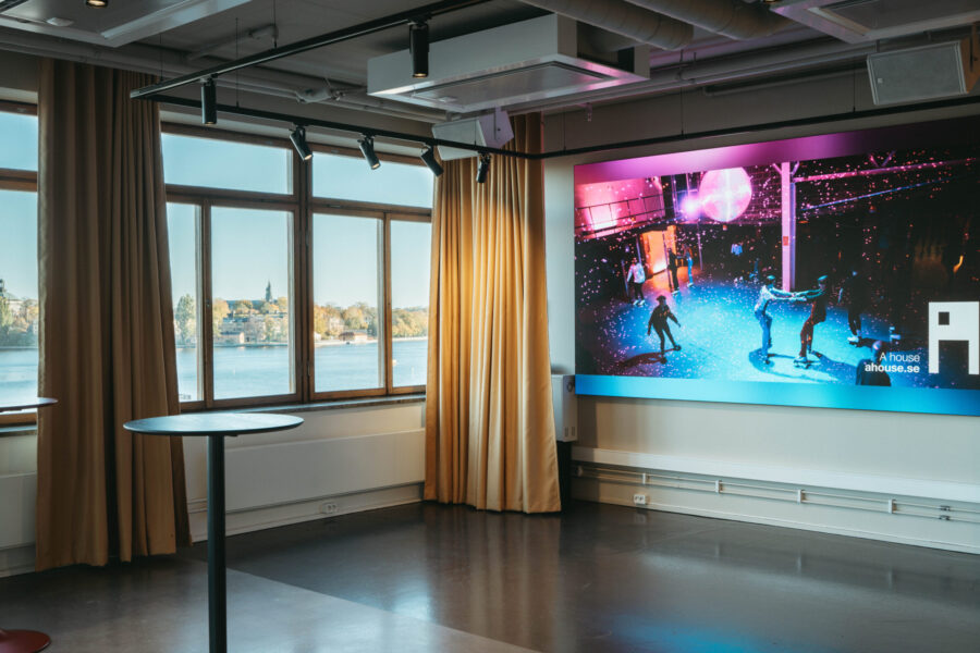 Minging area with high standing tables and wall-mounted monitor